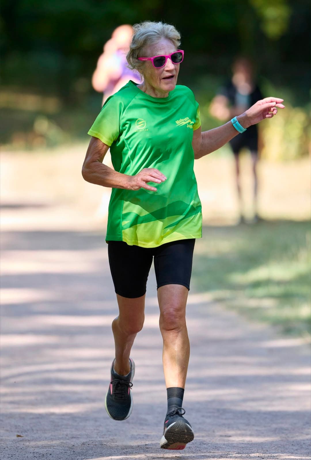 A smiling member in pink sunglasses running in club colours