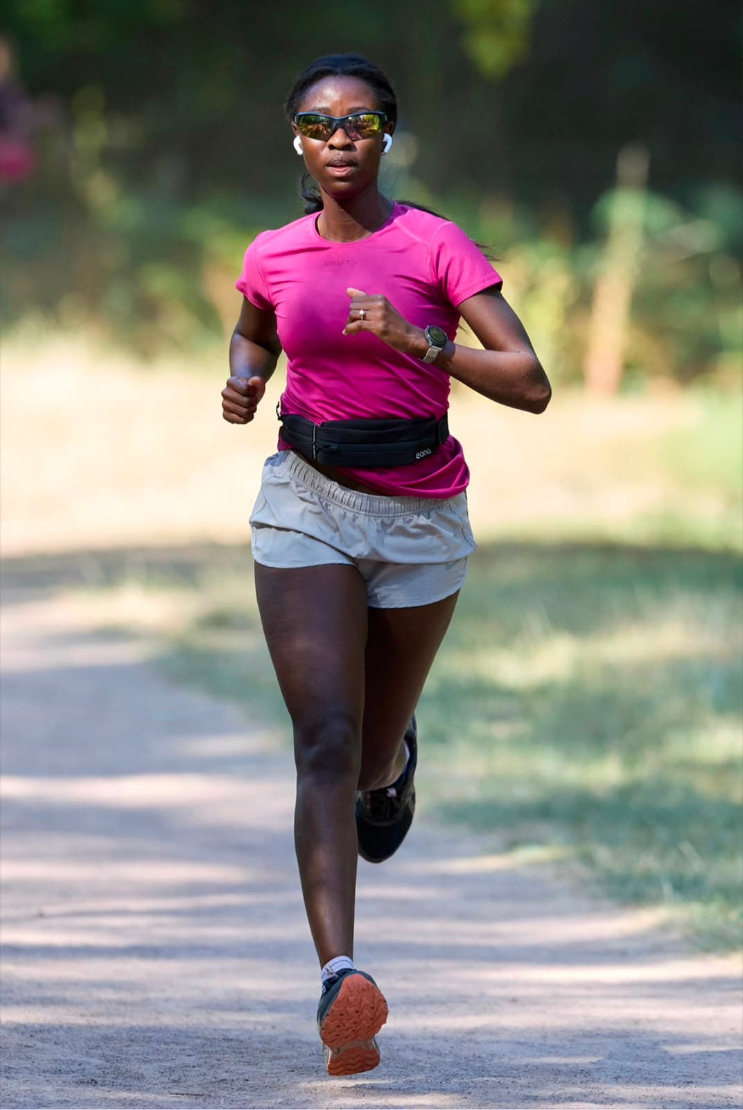 A member running a sunlit woodland path